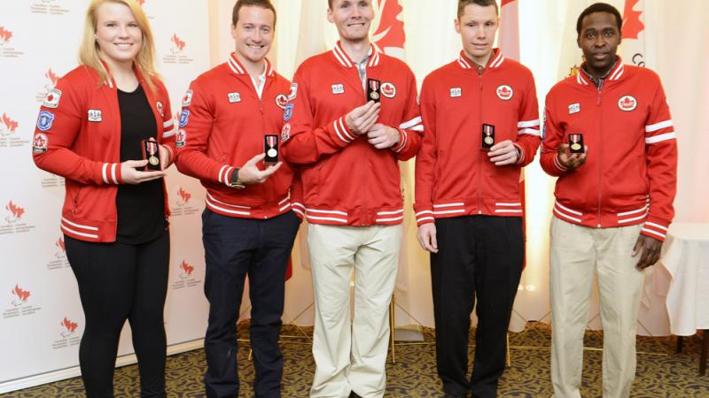 A picture of athletes posing for a group picture with their trophies