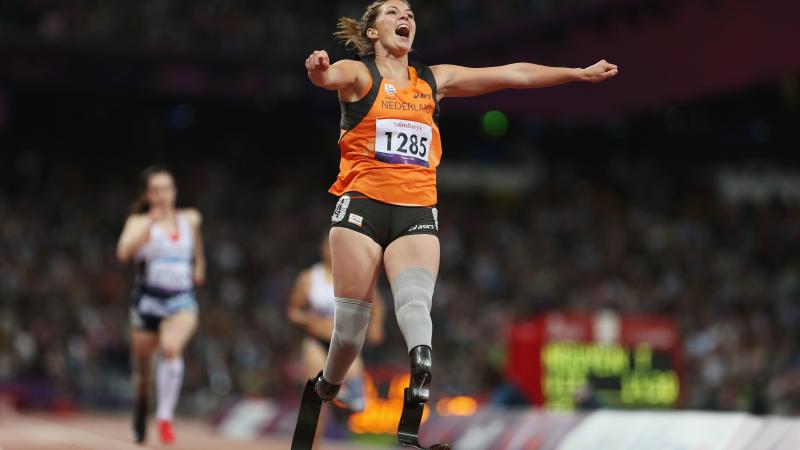 A picture of a woman on the running track celebrating with her hands spread