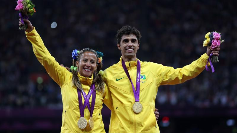 A picture of a woman and a man on a podium with medals around their neck