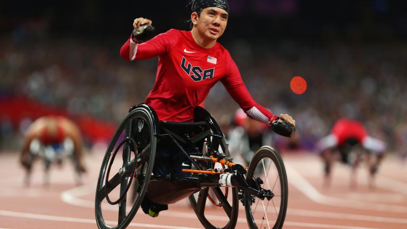 A picture of a man in a wheelchair celebrates after crossing a finish line