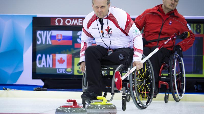 A picture of 2 mens in wheelchairs playing curling