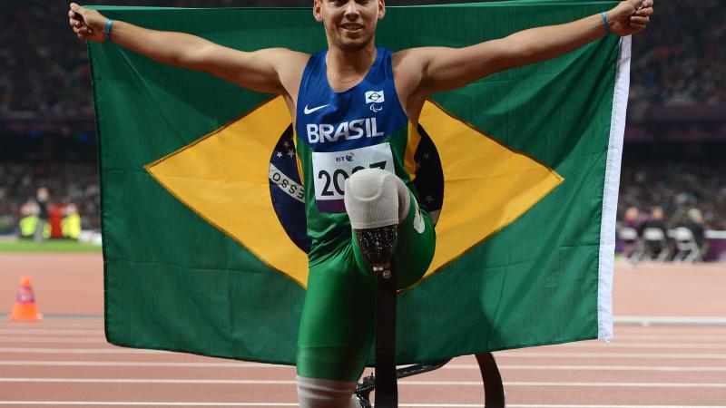 A picture of a man on the track posing with Brazilian flag in his hands