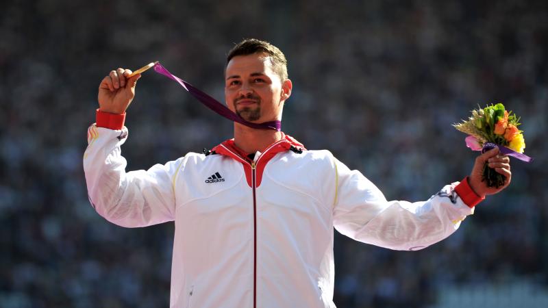 A picture of a man on a podium with a medal around his neck