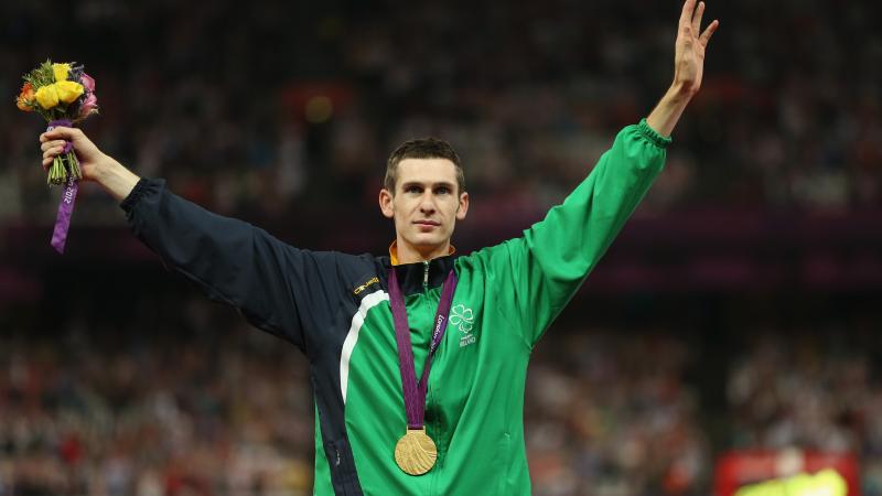 A picture of a man on a podium with a medal around his neck