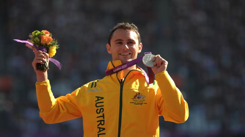 A picture of a man on a podium with a medal around his neck