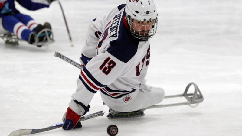 A picture of a man in a sledge playing ice hockey