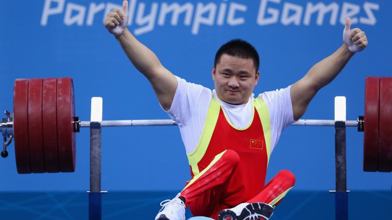 A picture of a man powerlifter on a bench celebrating with his hands up