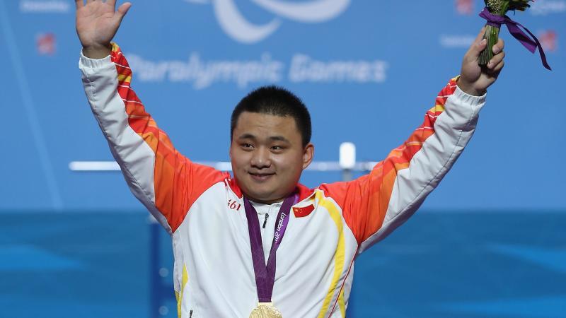 A picture of a man on a podium with a medal around his neck