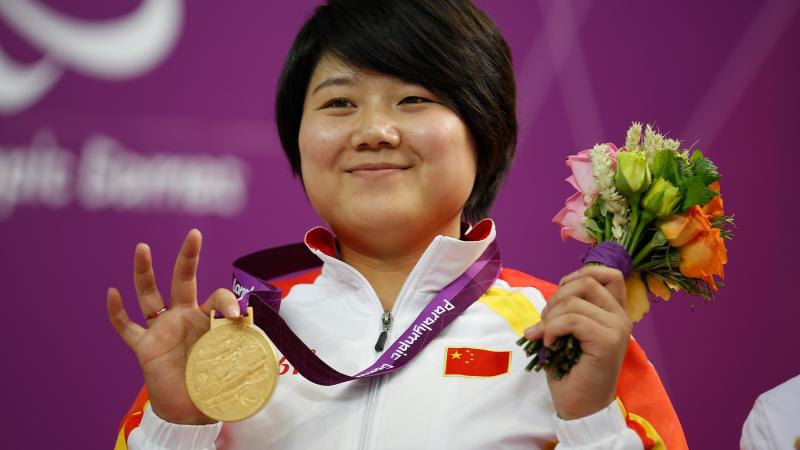 A picture of a woman on a podium with a medal around her neck