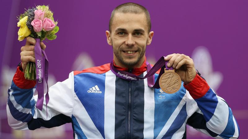 A picture of a man on a podium with a medal around his neck