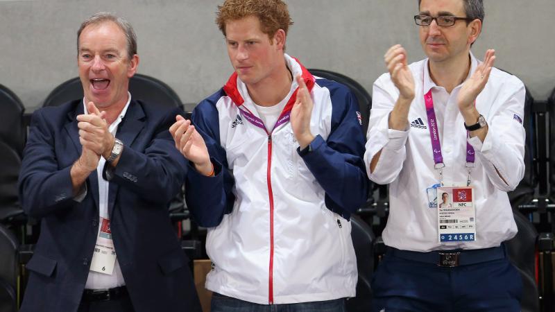 A picture of 3 men standing and applauding 