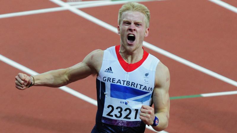 A picture of a man crossing a finish line during an athletics race and celebrating his victory