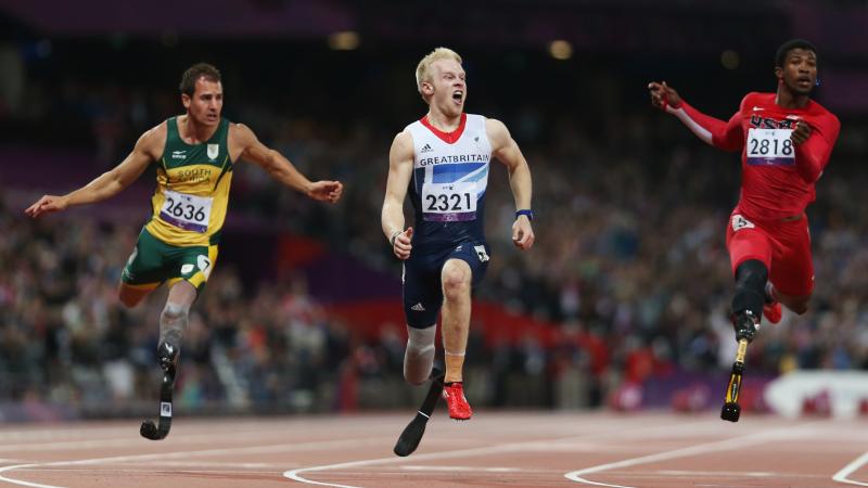 A picture of 3 men crossing the finish line during an athletics race