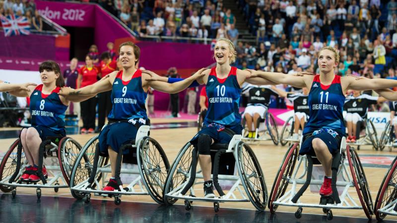 A picture of women in wheelchair posing for a group picture during a wheelchair basketball match