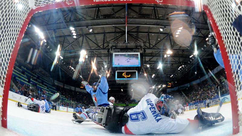 A picture of a man in a sledge celebrating his goal during an ice sledge hockey match.