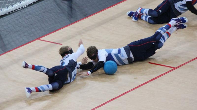 A picture of three blind men laying on the ground and trying to stop a ball