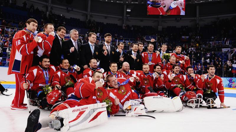 The entire Russian ice sledge hockey team poses with their medals on the ice facing the camera. 