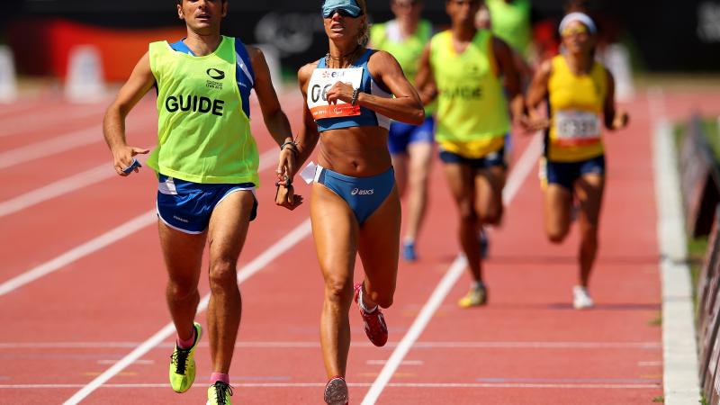 A visually impaired women and her guide running on the track of a stadium