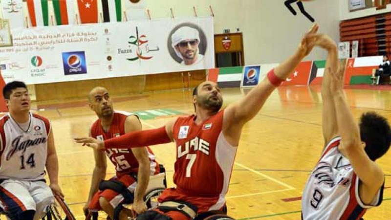 A man in a wheelchair shoots a basketball layup. 