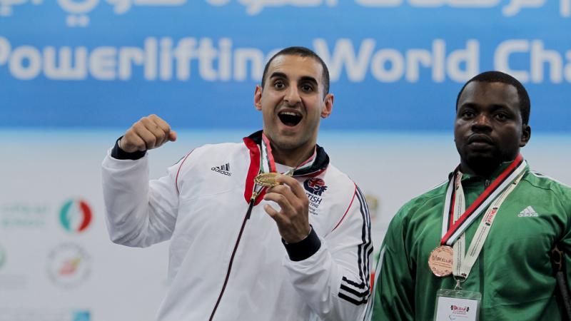 An athlete poses showing his gold medal.