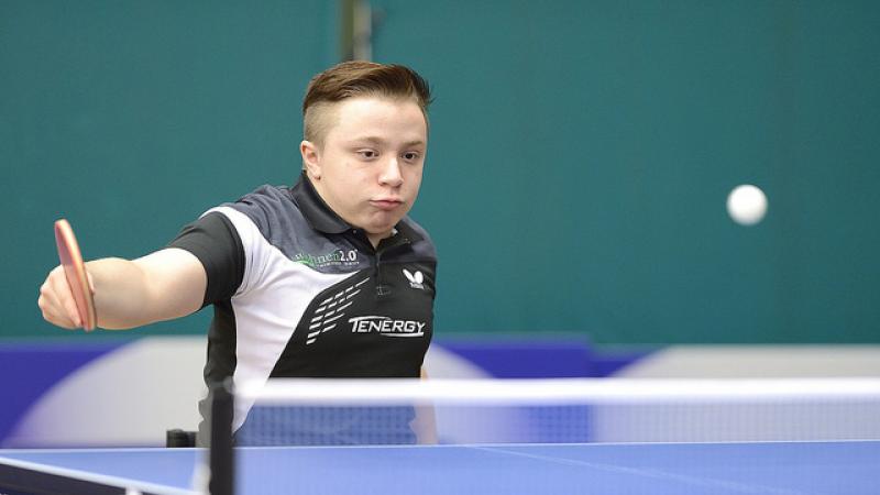 An athlete hits a table tennis ball. 