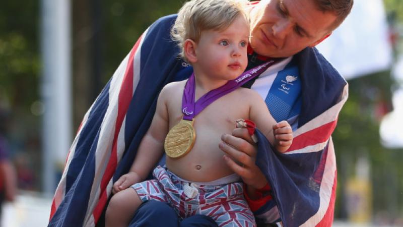 A picture of man in a wheelchair holding his baby after his victory