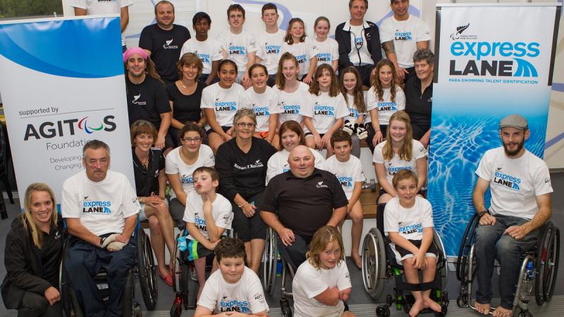 A group of participants pose in front of Paralympics New Zealand and Agitos Foundation banners.