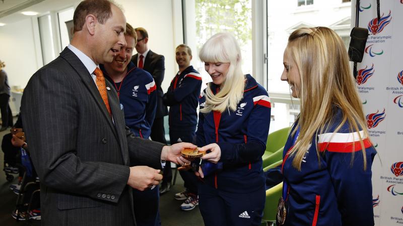 A man reaches out to look at Kelly Gallagher's Sochi 2014 gold medal.