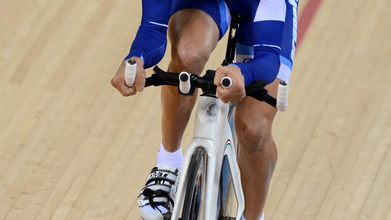 A man cycles straight ahead on a track.