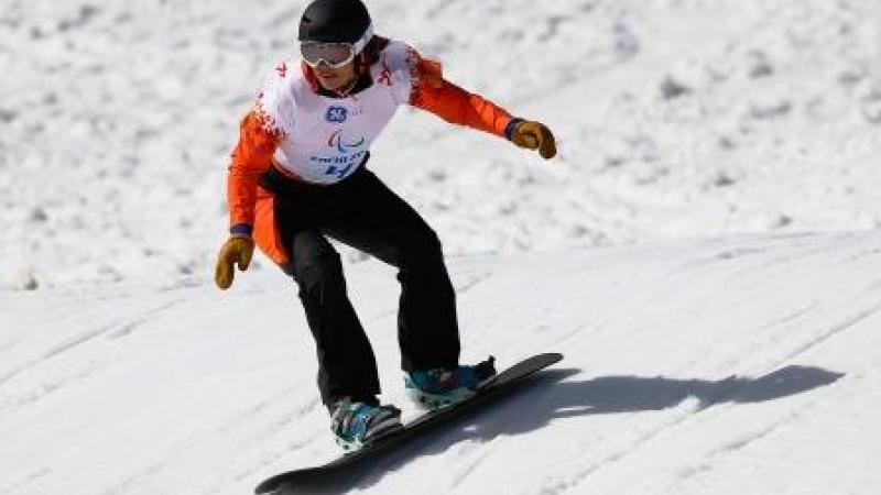 A female snowboarder rides down a slope