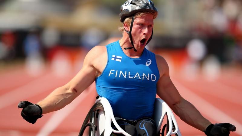 An wheelchair racer shouts out after crossing the finish line in first place.