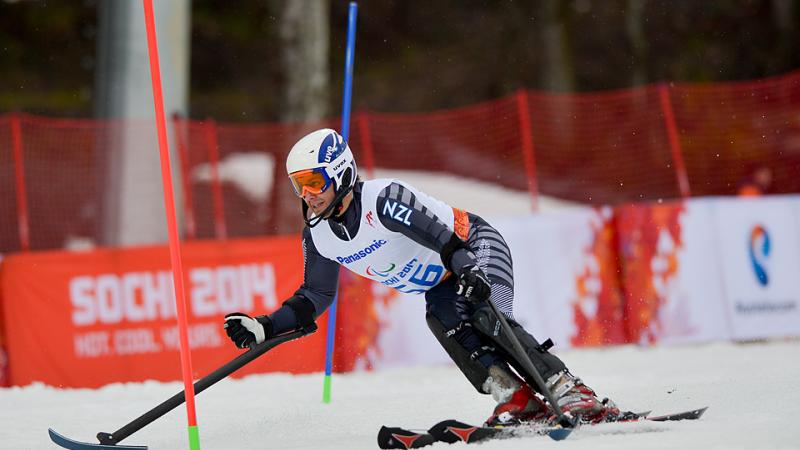 Skiing man curving around some slalom poles