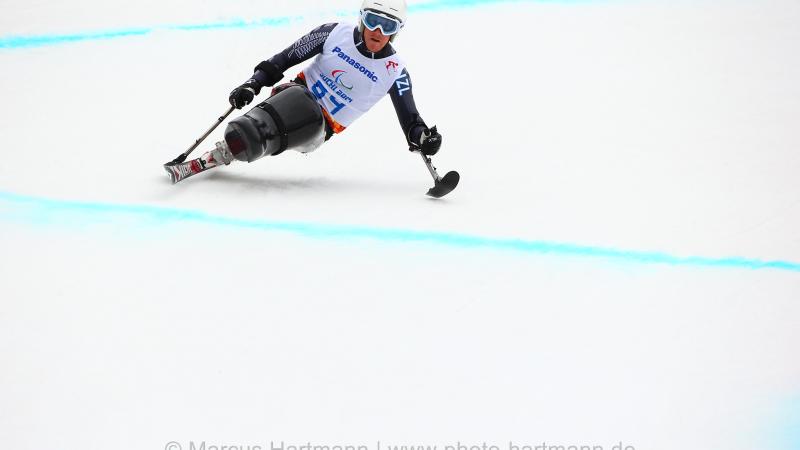 Sit skier going down a slope leans to his left