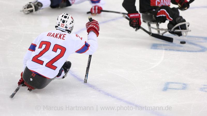 two Para ice hockey players close in on the puck