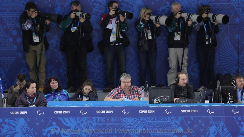 A row of sport photographers taking pictures of ice sledge hockey at Sochi 2014.