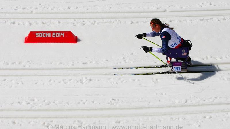 Women in sit ski on a cross country track