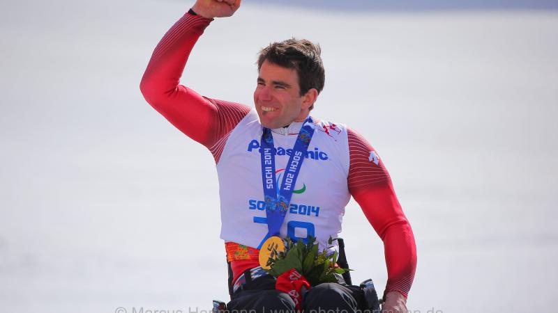 Upper body of man in wheelchair celebrating with medal around his neck