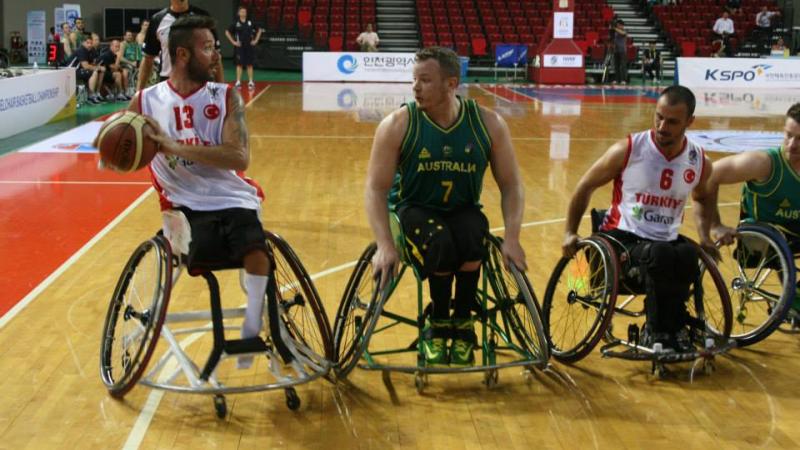 Three wheelchair basketball players fight for the ball