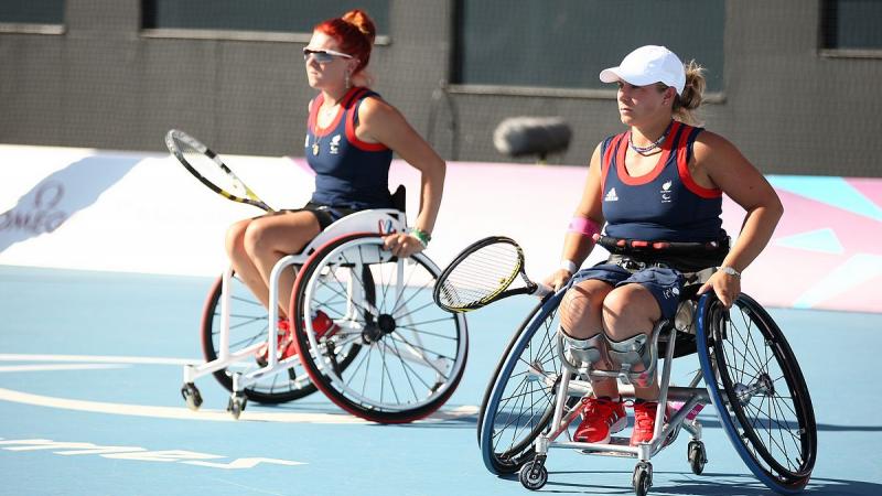 Two women in wheelchairs with tennis rackets during a match