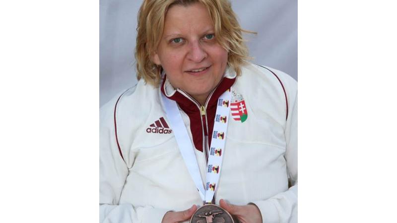 Upper body of women showing a medal to the camera