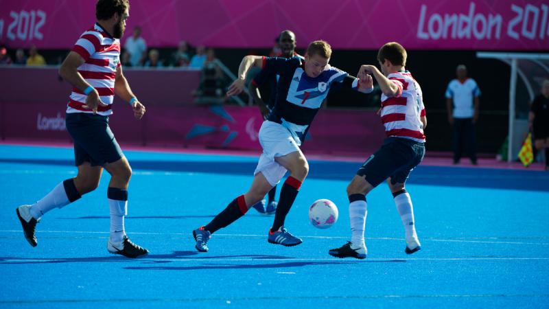 Defender trying to stop a football player on a blues field of play