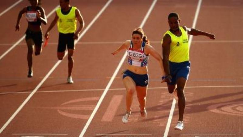 Two runners cross the finish line in a stadium