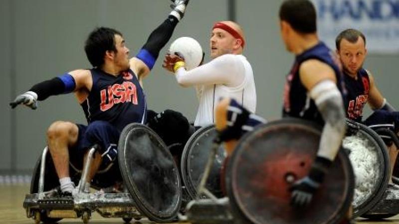 Two wheelchair rugby players fight for the ball on the field of play
