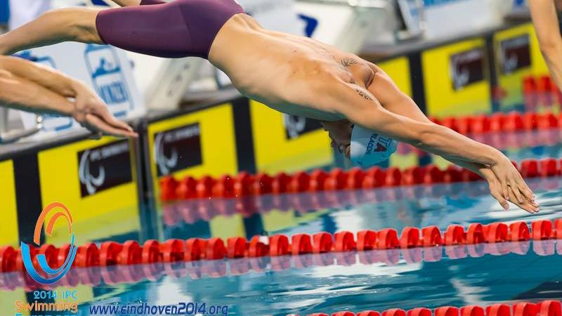 A swimmer diving into the pool at the start of a race.