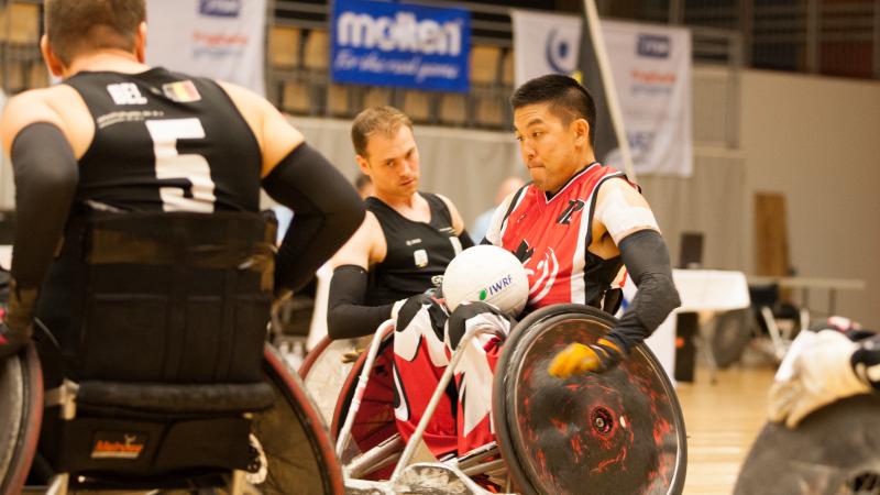 Man in a wheelchair with a ball in his lap going forward.