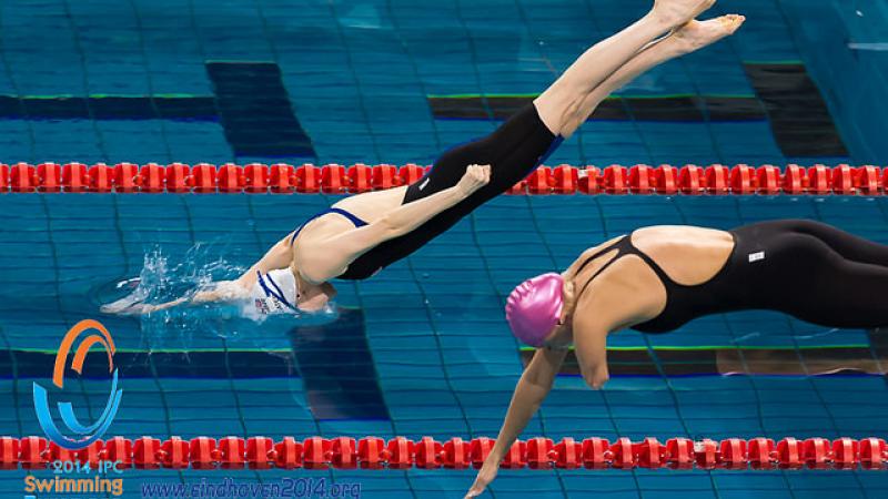 Two female athletes dive into the pool at the 2014 IPC Swimming European Championships