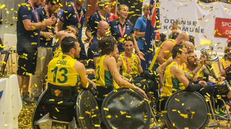 Men in wheelchairs with a big championships trophy