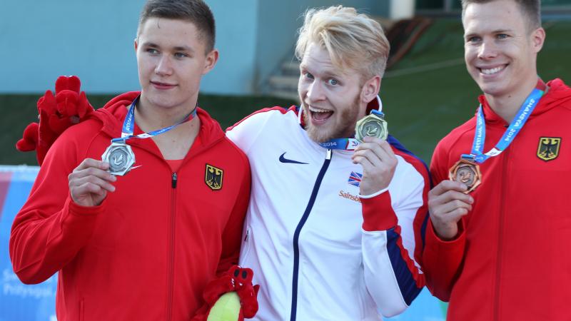 3 upper bodies of athletes on the podium, posing and showing their medals.