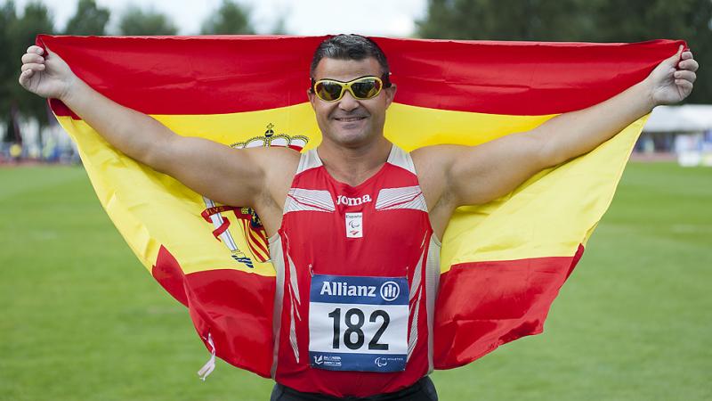 Man with a spanish flag celebrating on a field of play in a stadium