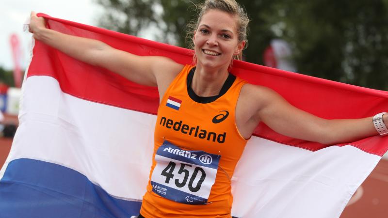 Women with a Dutch flag smiles to the camera